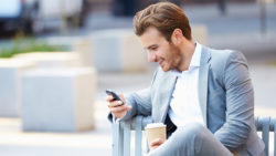 Man outside smiling with phone
